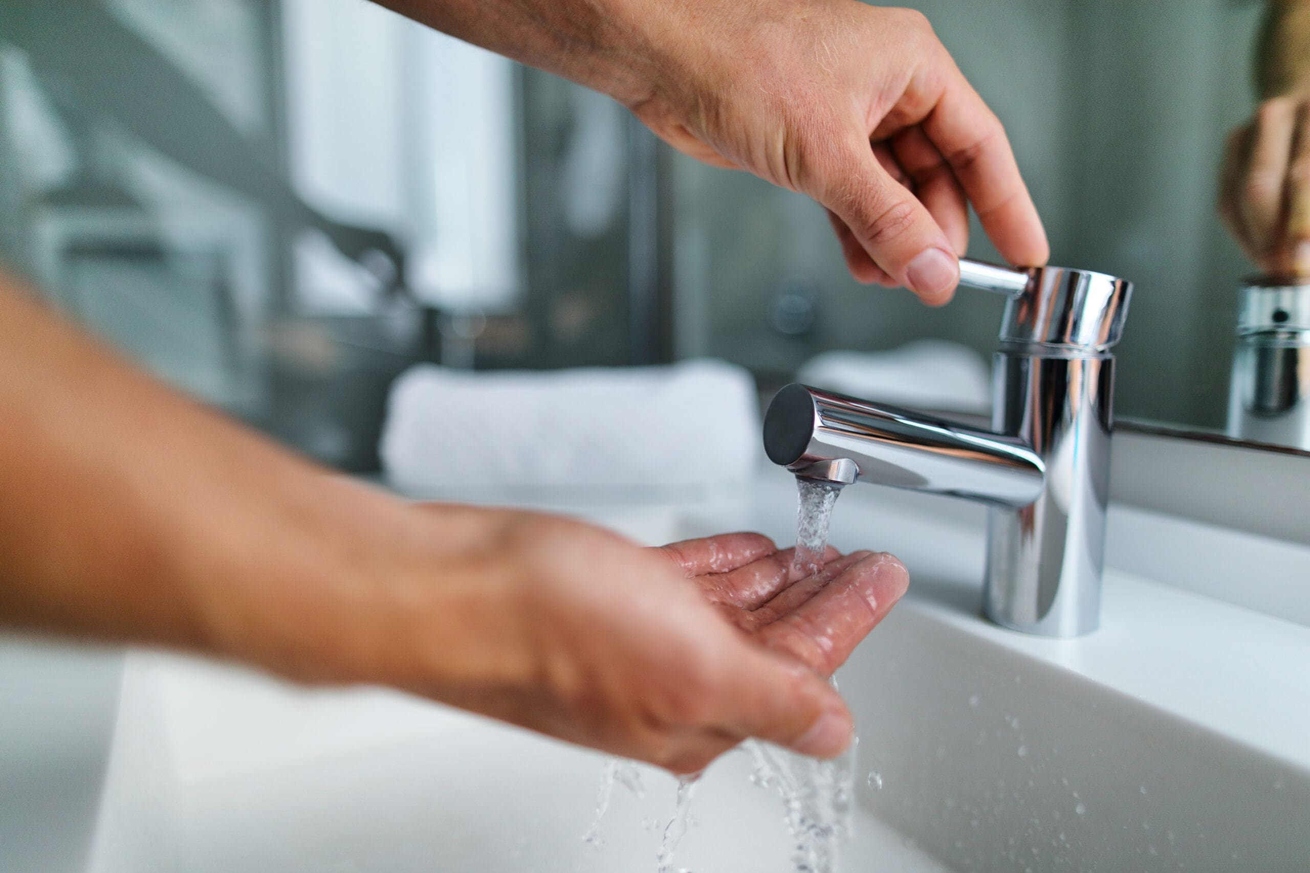 Person washing hands under shiny tap